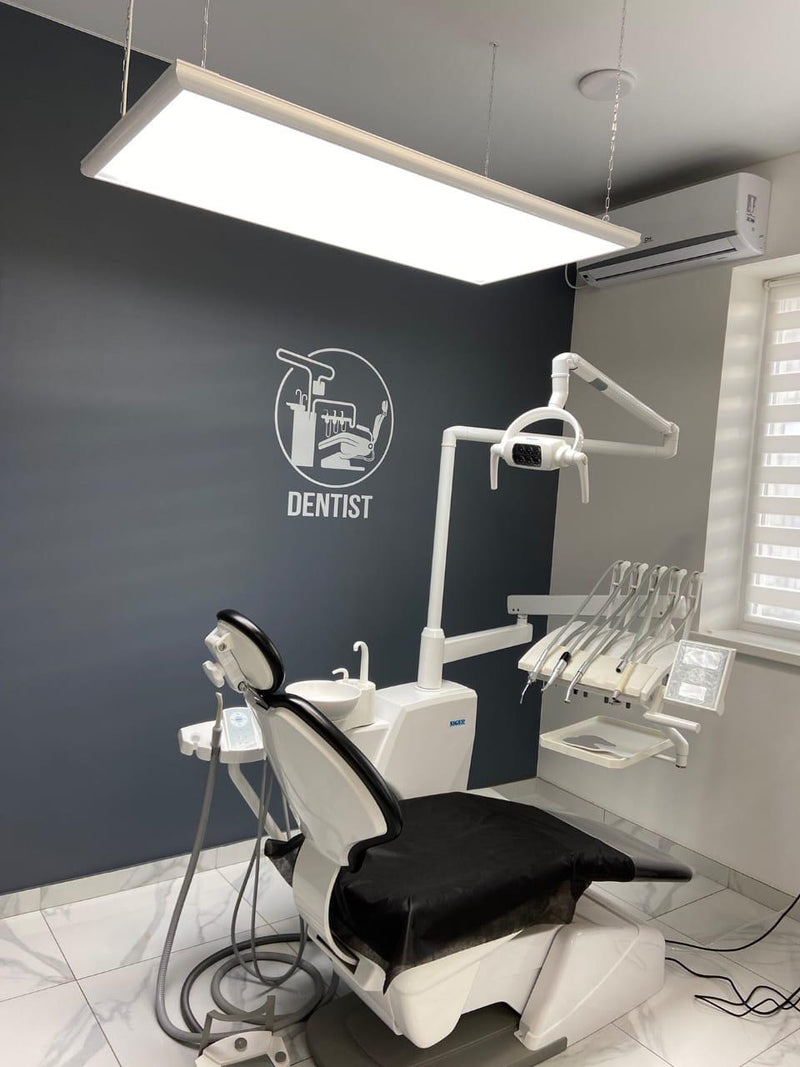 Dental office interior with a chair, shadowless lights by Pro Max Dental, and equipment against a dark wall with 'DENTIST' text.