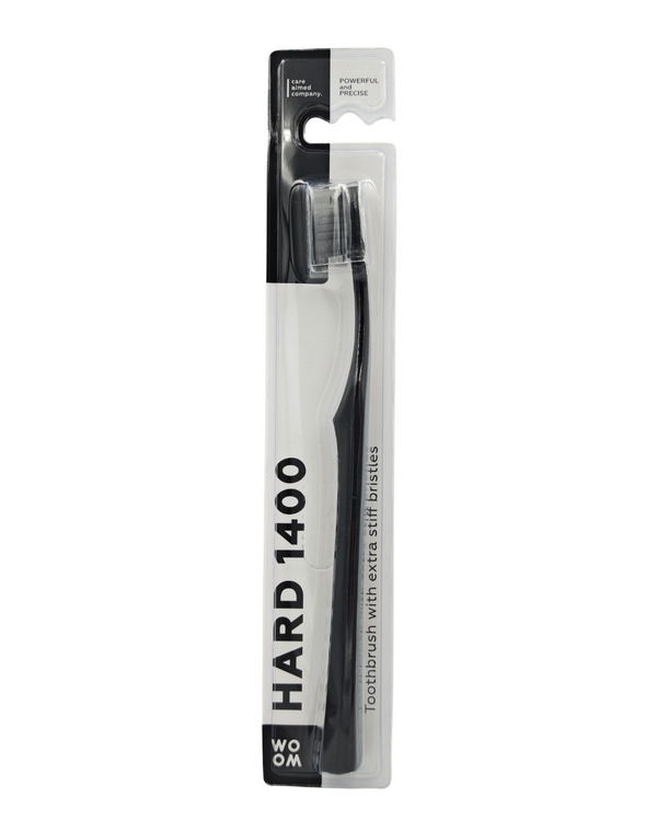 A black WOOM HARD 1400 toothbrush in its packaging, displaying the toothbrush with white and dark gray bristles and the brand name on the handle.