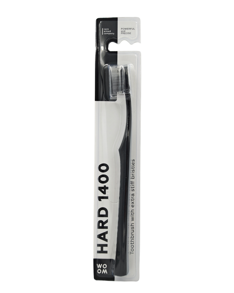 A black WOOM HARD 1400 toothbrush in its packaging, displaying the toothbrush with white and dark gray bristles and the brand name on the handle.
