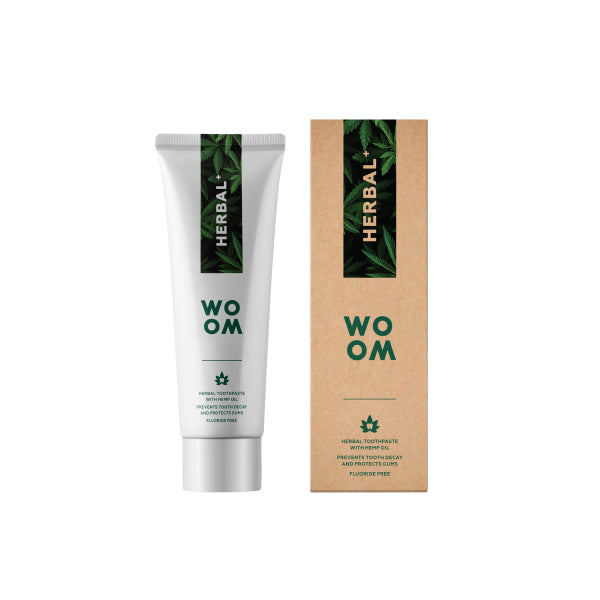 A tube of herbal+ toothpaste next to its packaging, both featuring the brand name WOOM.