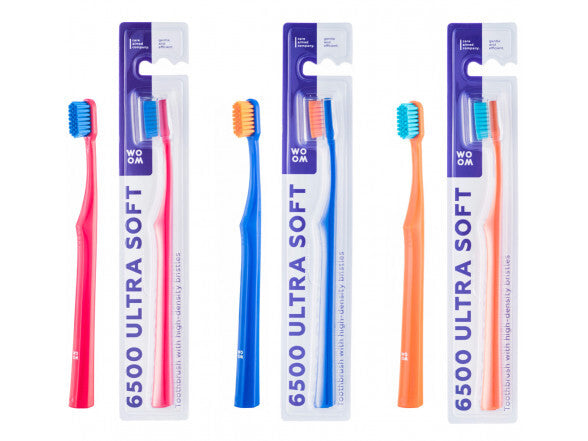 Three toothbrushes with ultra soft bristles in red, blue, and orange colors, each packaged in individual cardboard slots with product information.